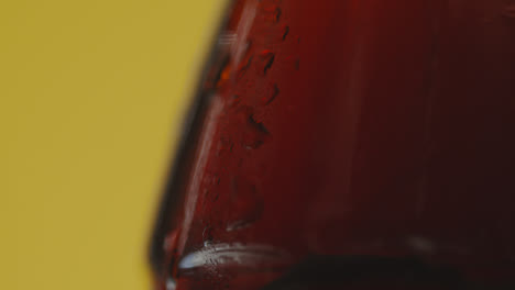 Close-Up-Of-Condensation-Droplets-Running-Down-Bottle-Of-Cold-Beer-Or-Soft-Drink-Against-Yellow-Background